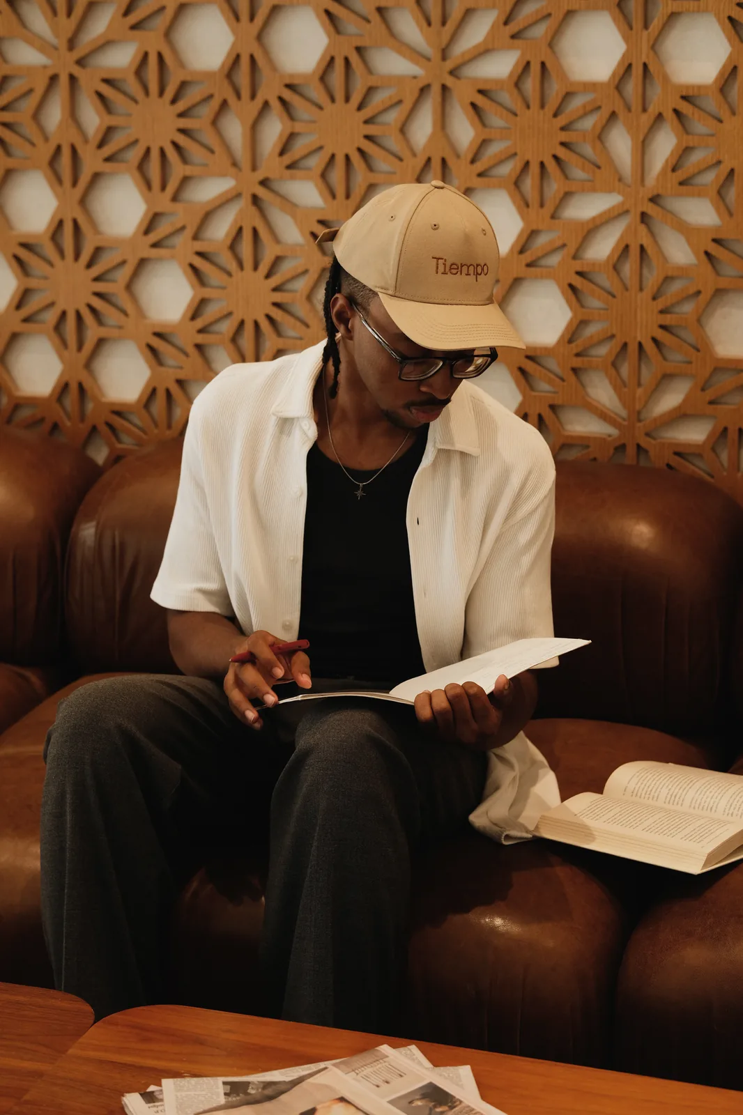A Tiempo assistant in a Tiempo cap reading through notes on a leather couch
