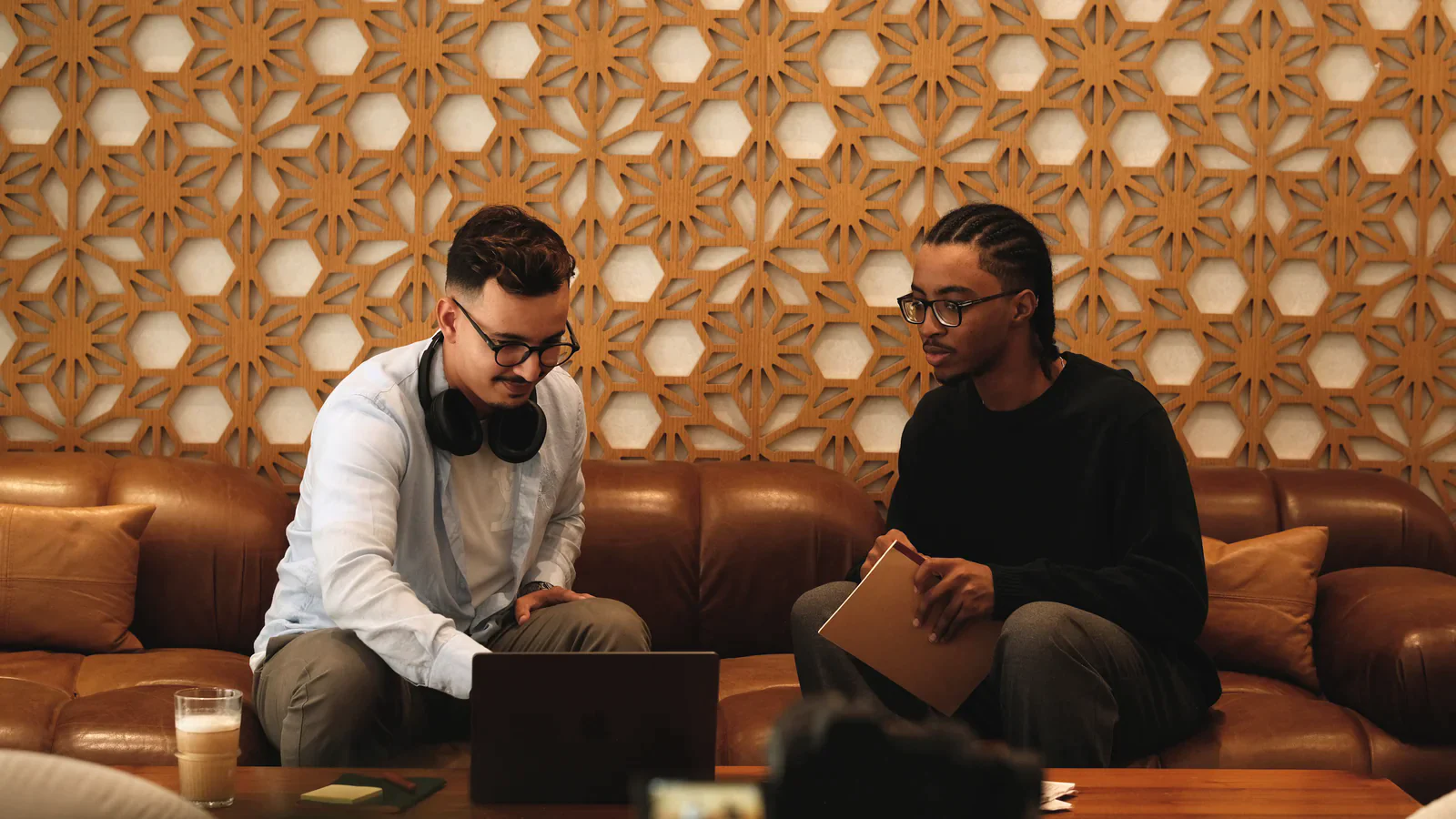 Two Tiempo team members working together on a couch, one on a laptop with headphones