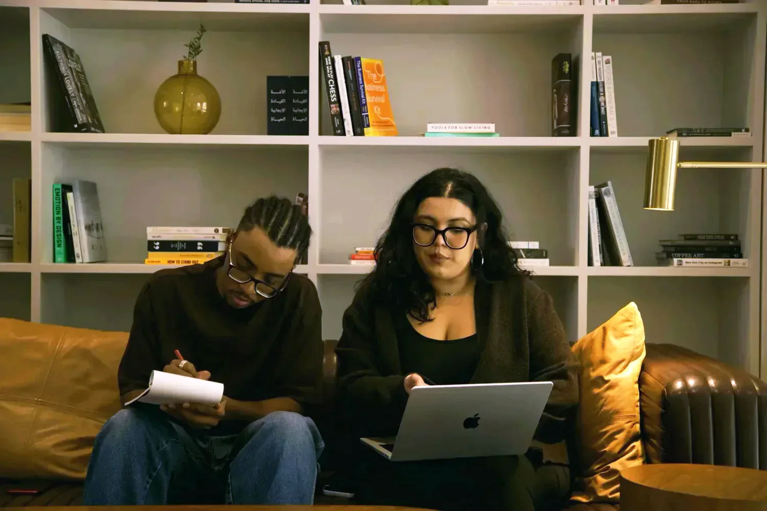 Two Tiempo team members working together, one on a laptop and one taking notes