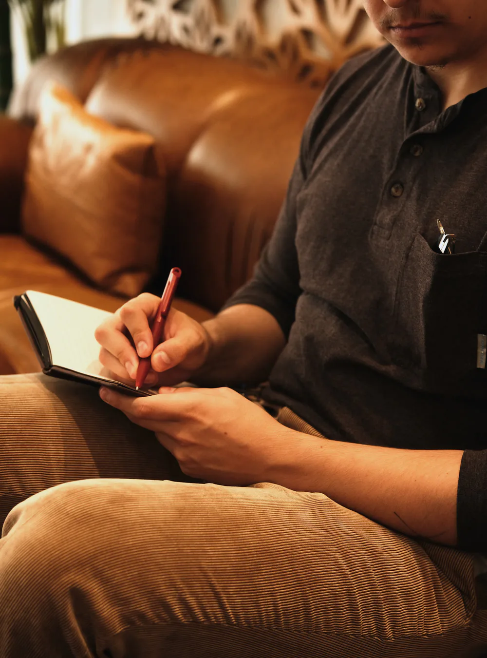 A Tiempo team member writing in a notebook on a leather couch
